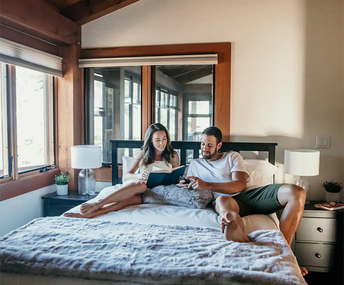 couple sitting on bed reading and looking on phone